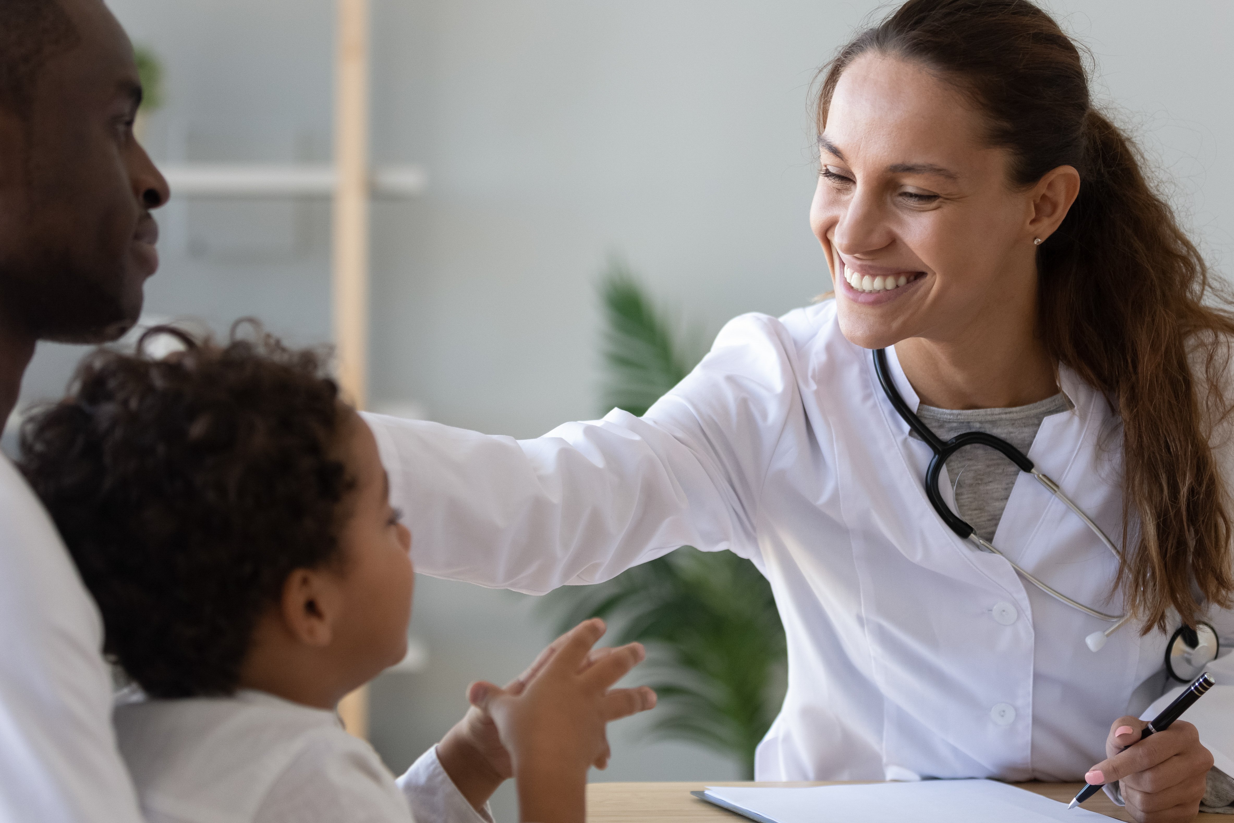 Friendly female doctor stroke head of cute African child boy.